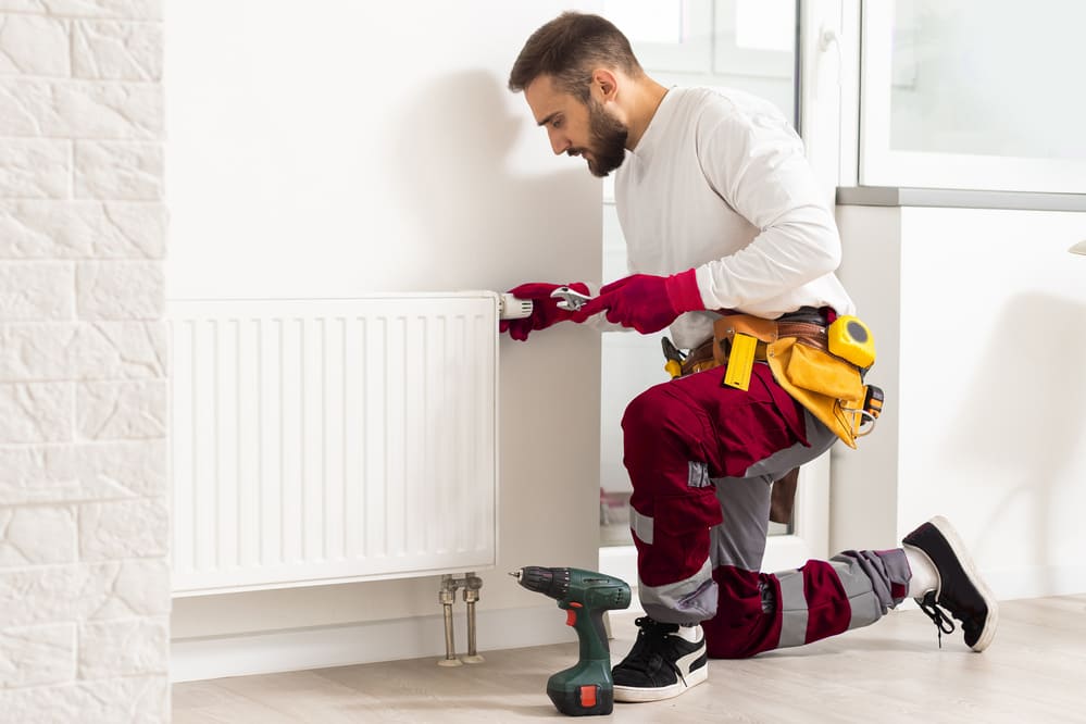 Chauffagiste réglant un radiateur